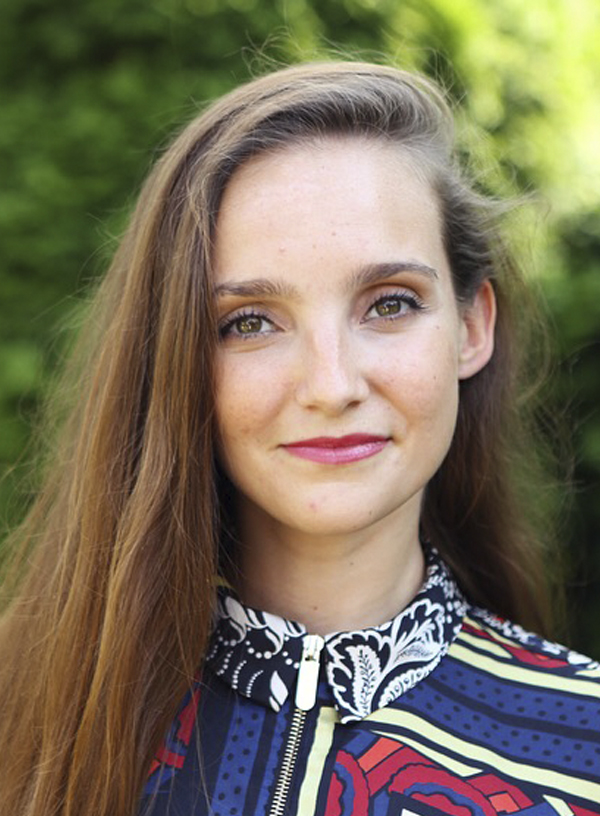 a headshot of Emily, a white woman with long, straight brown hair wearing a colourful shirt