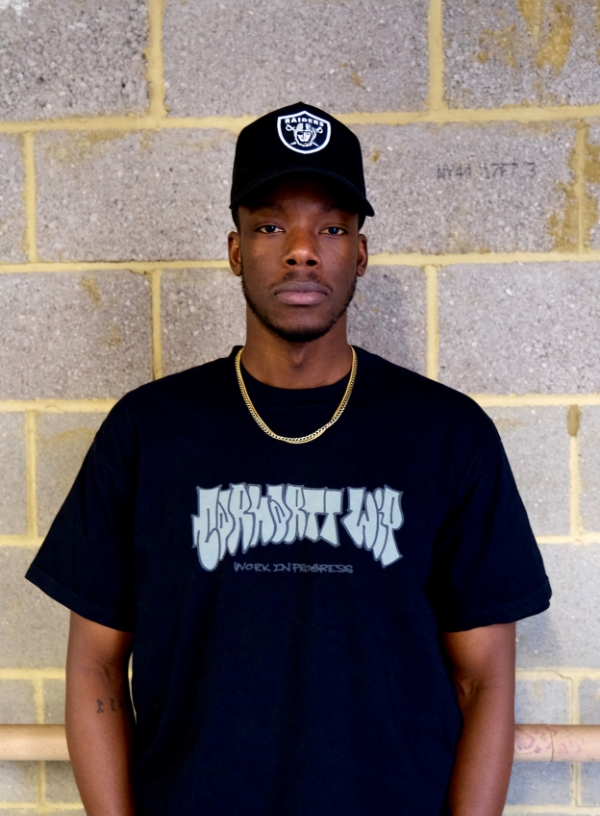 a young man standing in front of a brick wall