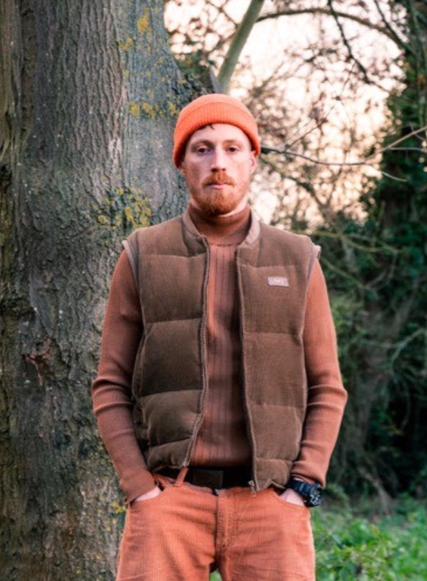 a man standing next to a tree in a forest