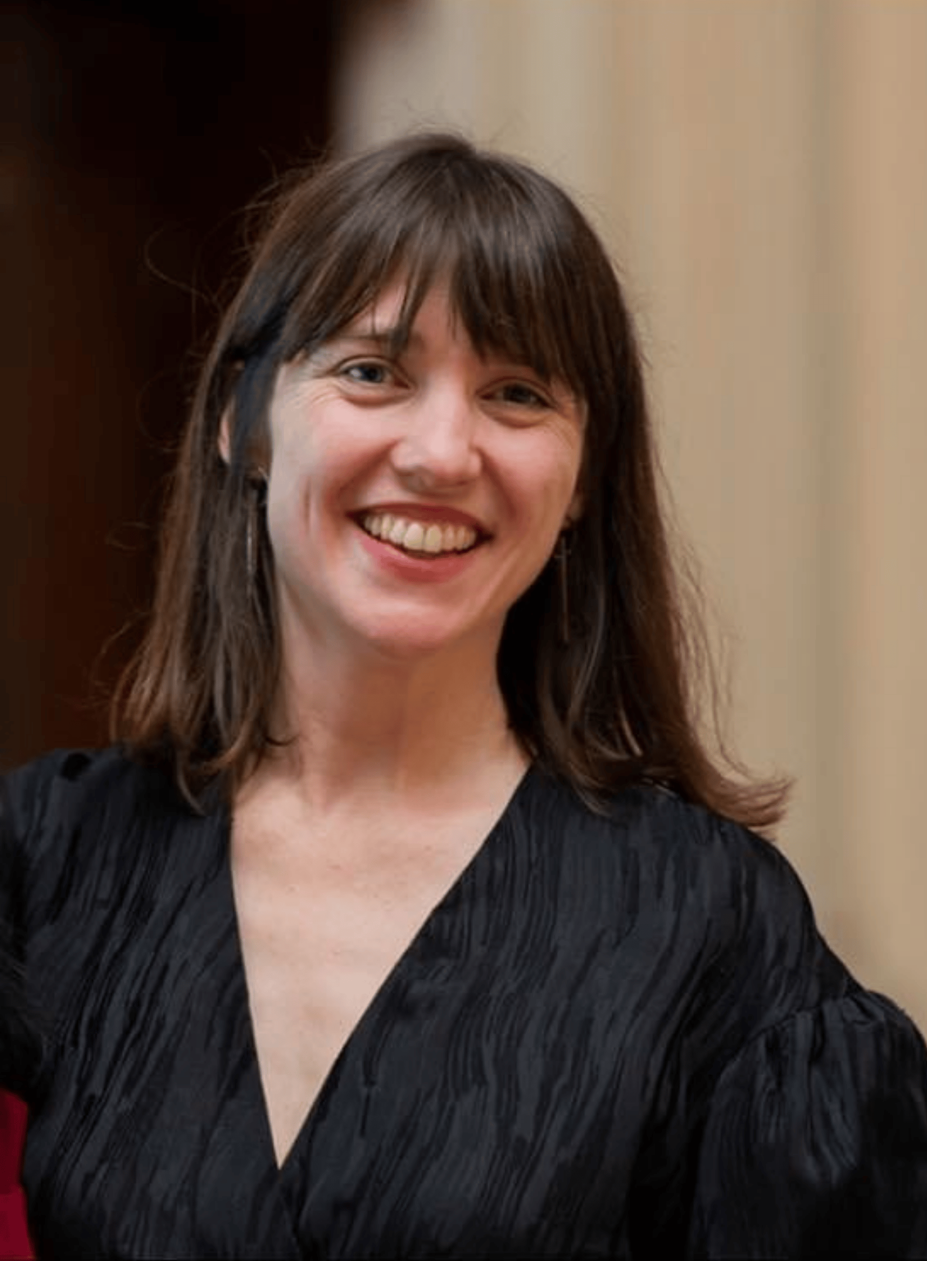 Headshot of Lily Dettmer, a fair skinned woman in her 30s with long dark hair, wearing a black top.