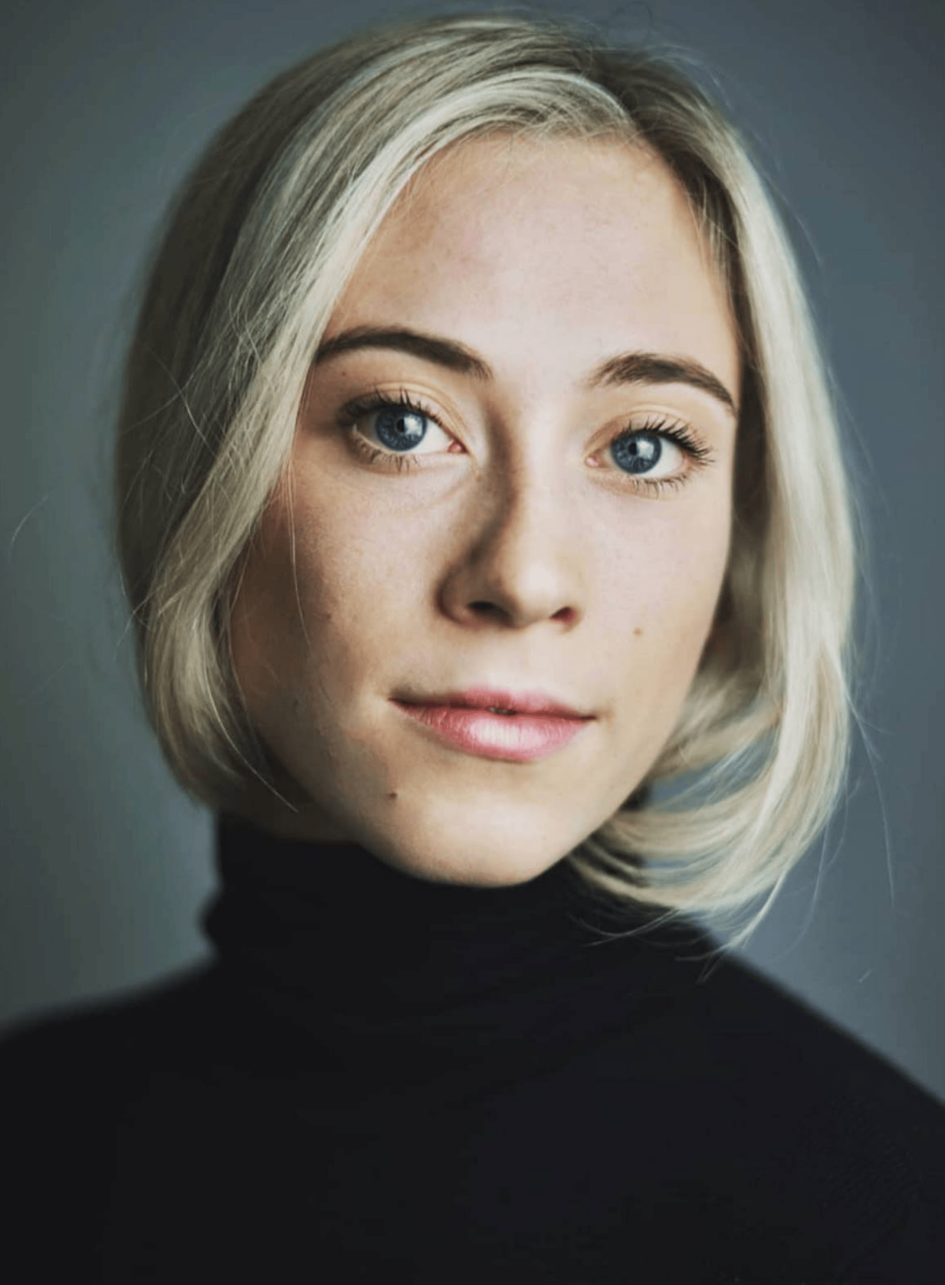 Headshot of Carina Howard, a fair skinned woman in her 30s with blonde hair, wearing a black polo neck top