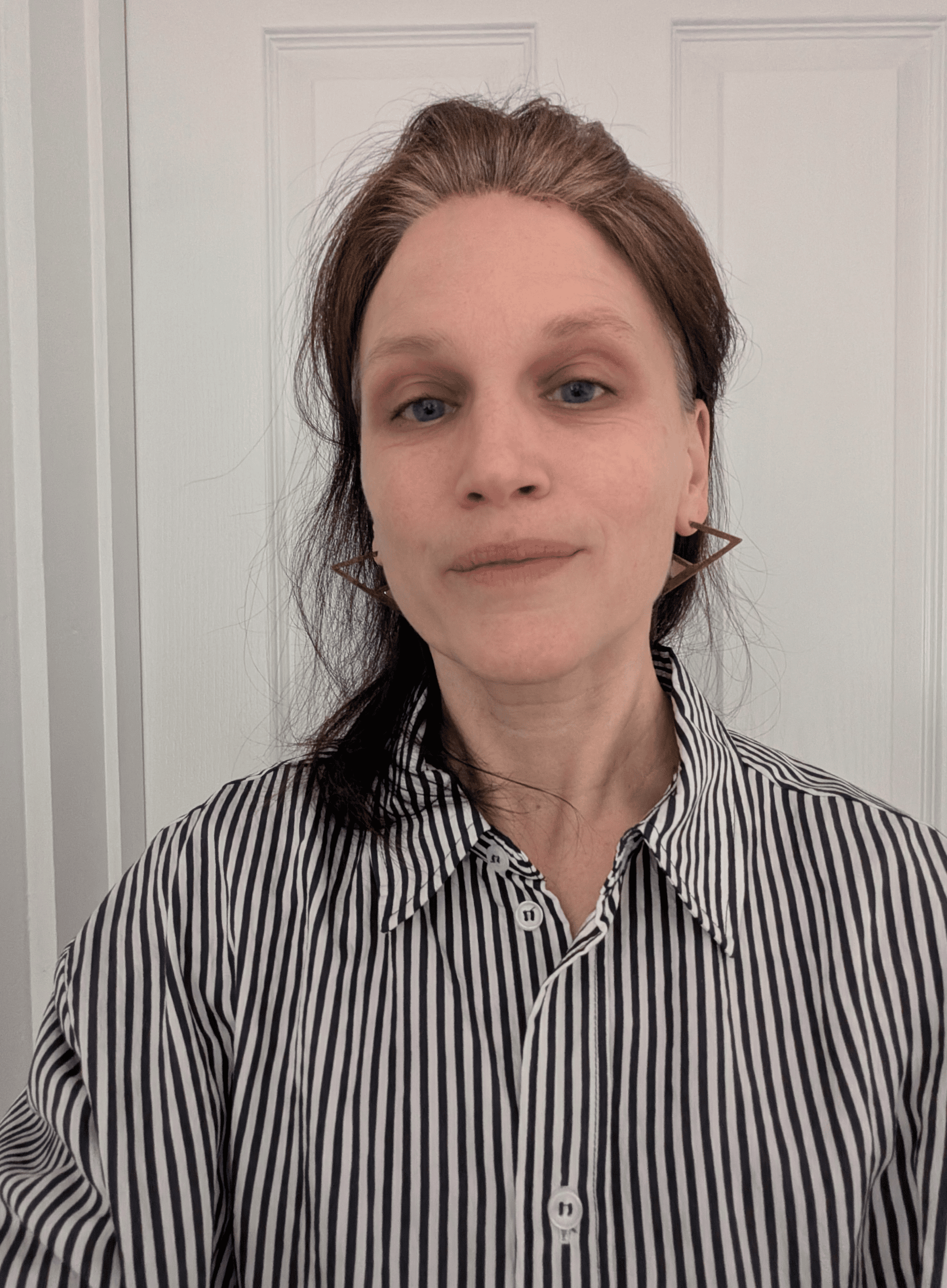 Headshot of Bettina Carpi, a fair skinned woman in her 40s with brown long hair tied back off her face. She is wearing a loose-fitting brown and white striped shirt.