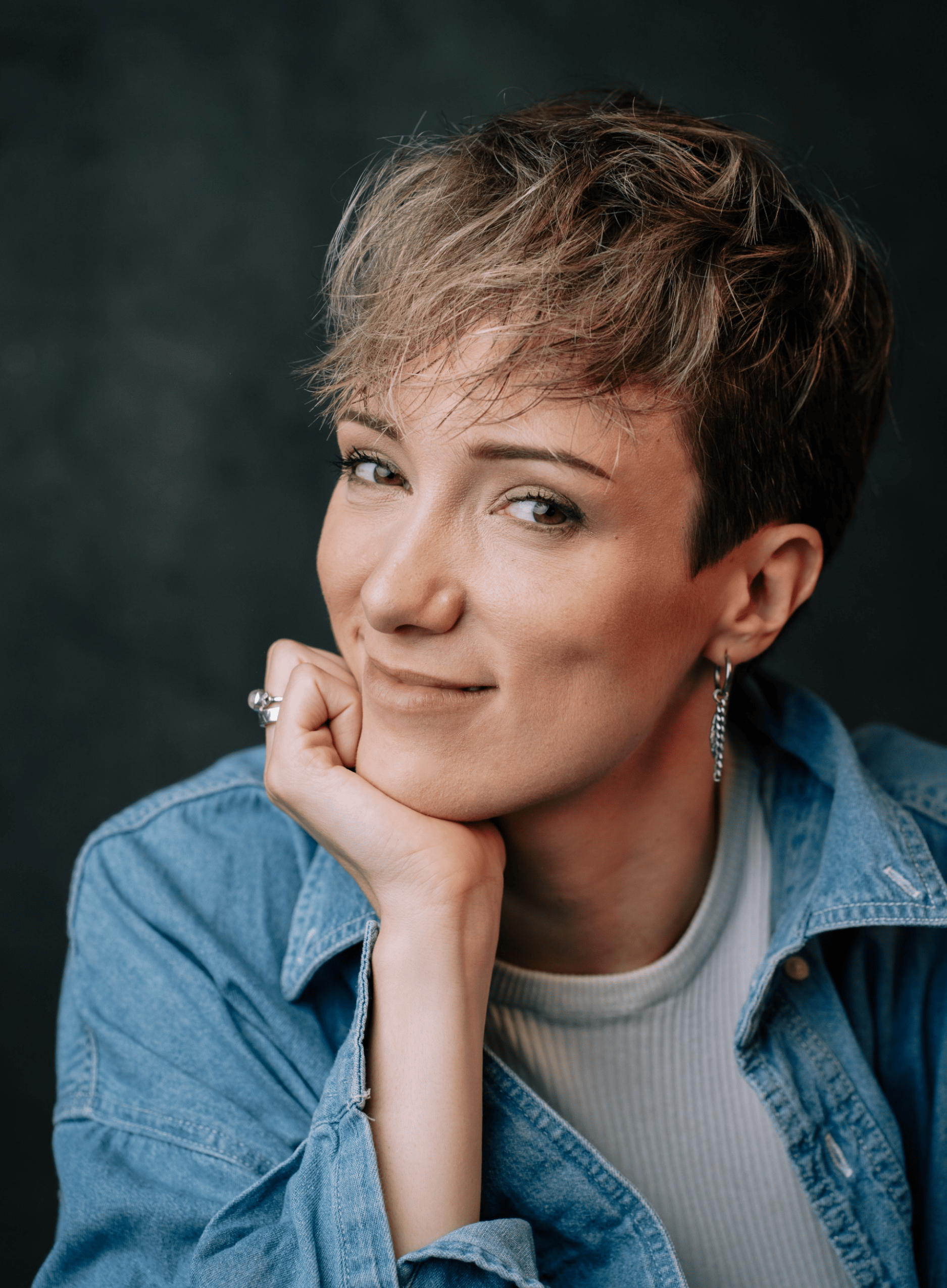 Headshot of Hannah Chandler, a fair skinned woman in her 30s with short blonde/brown hair. She is wearing a light denim shirt over a white top, and silver jewellery.