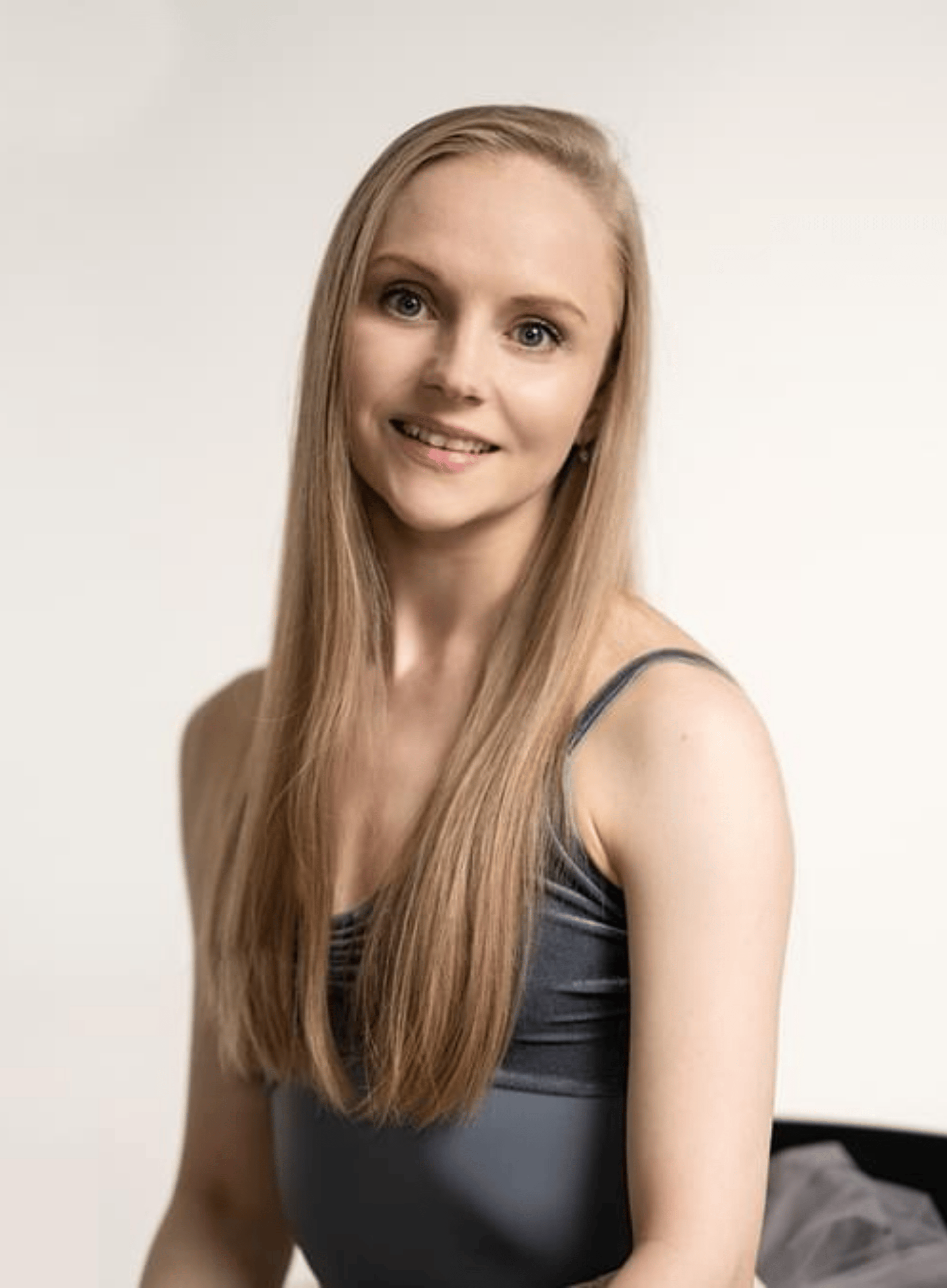 Headshot of Karla Doorbar, a fair skinned woman in her 30s with long, straight blonde hair, wearing a grey leotard.