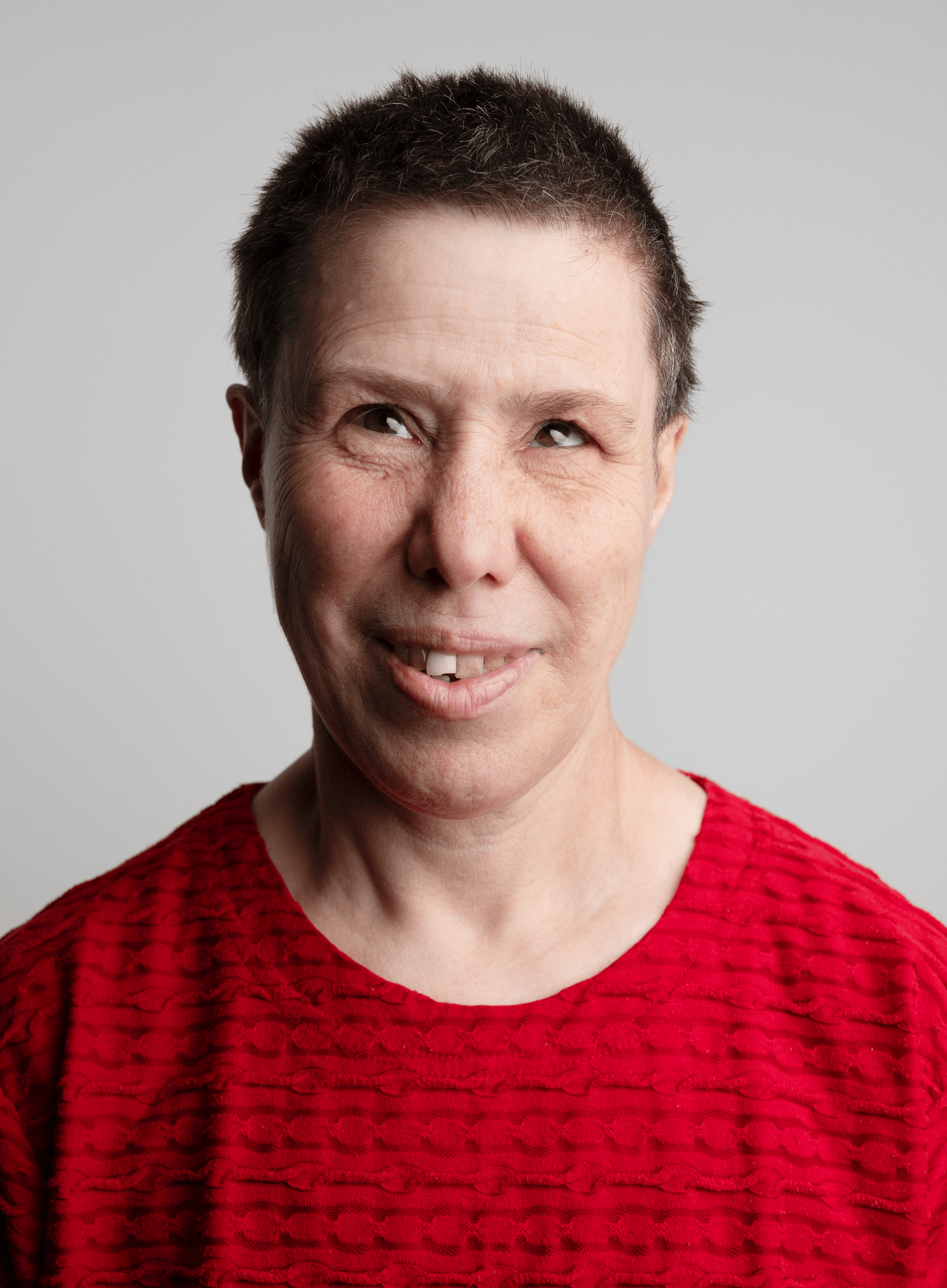 Headshot of Kavina Pound, a fair skinned woman in her 40s with very short brown hair, wearing a red top.