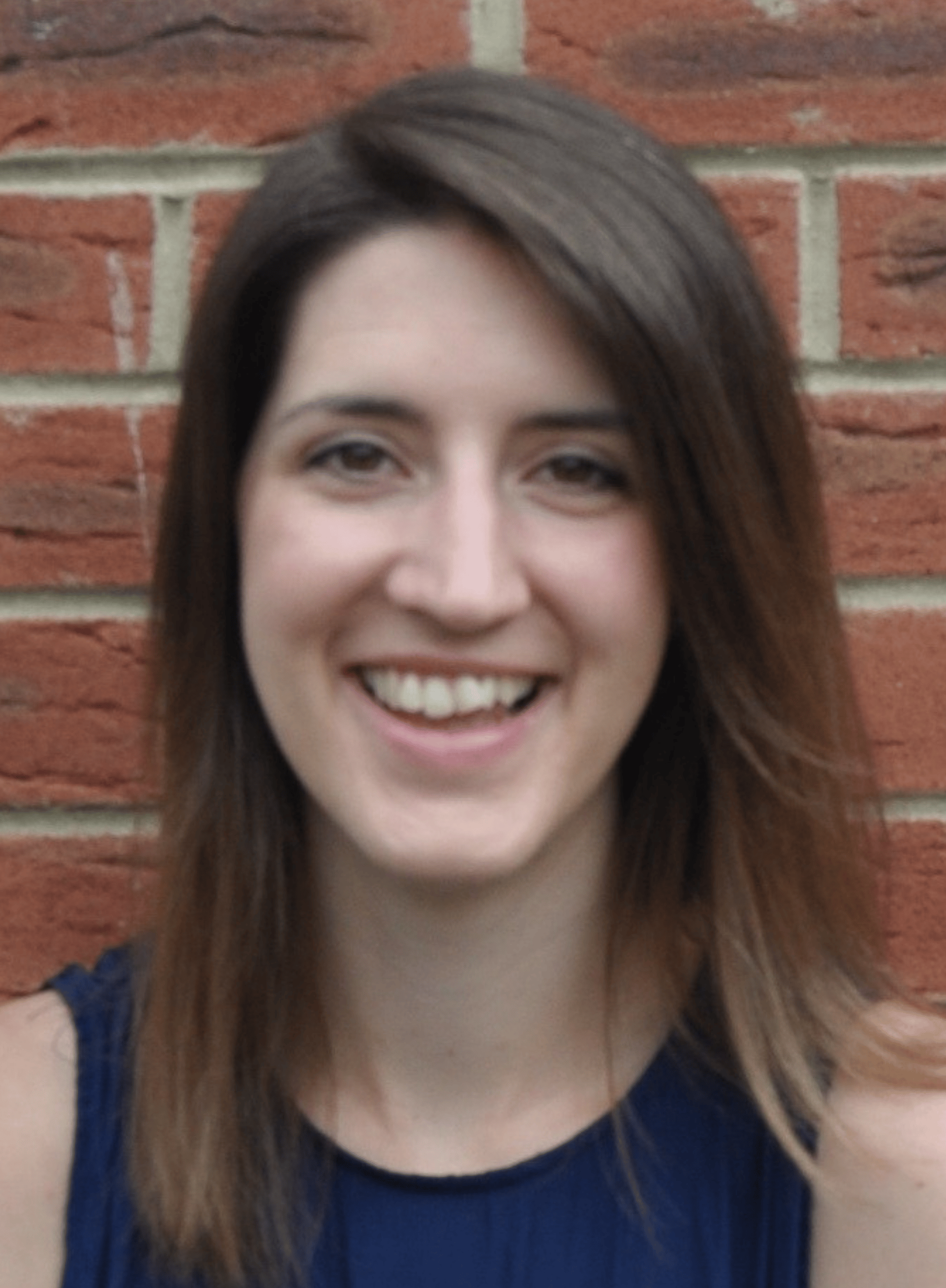 Headshot of Laura Rolinson, a fair skinned woman in her 30s with long, straight brown hair, wearing a blue sleeveless top and smiling towards the camera.