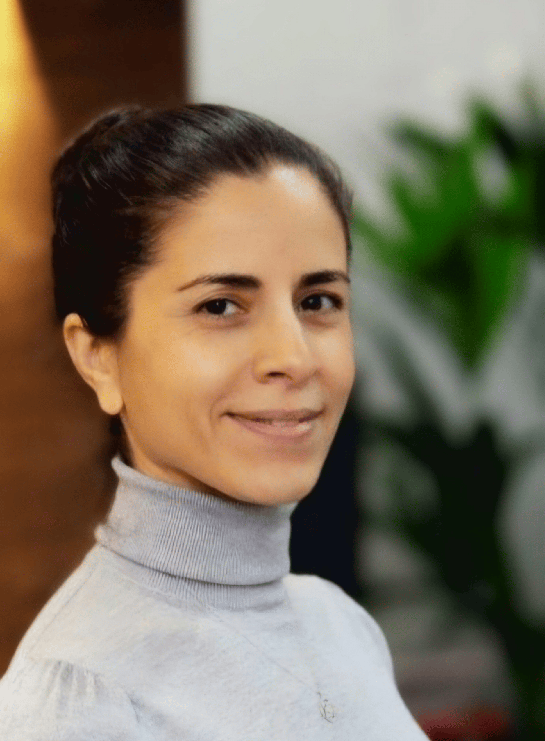 Sonya is a woman in her 40s with black hair tied back. She is wearing a grey turtle neck sweater.